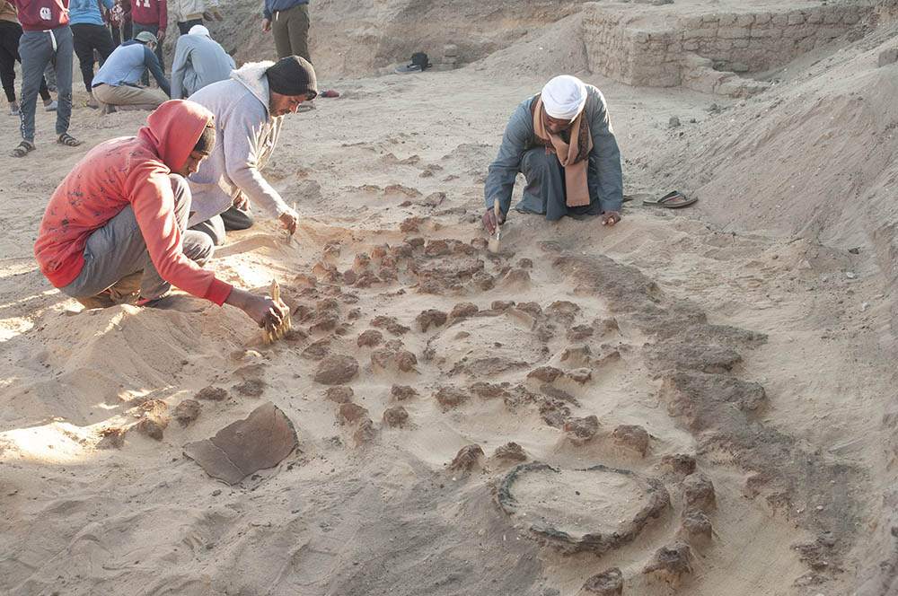Close up photograph of conservator excavating coffin with small tools.