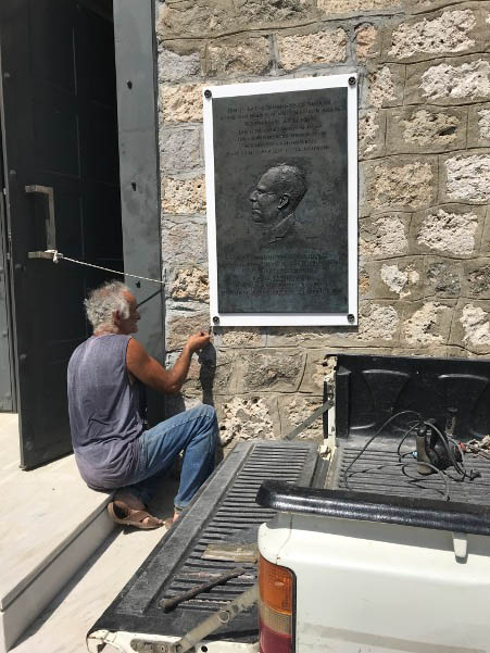 cKnelleing worker installing plaque on exterior of museum.