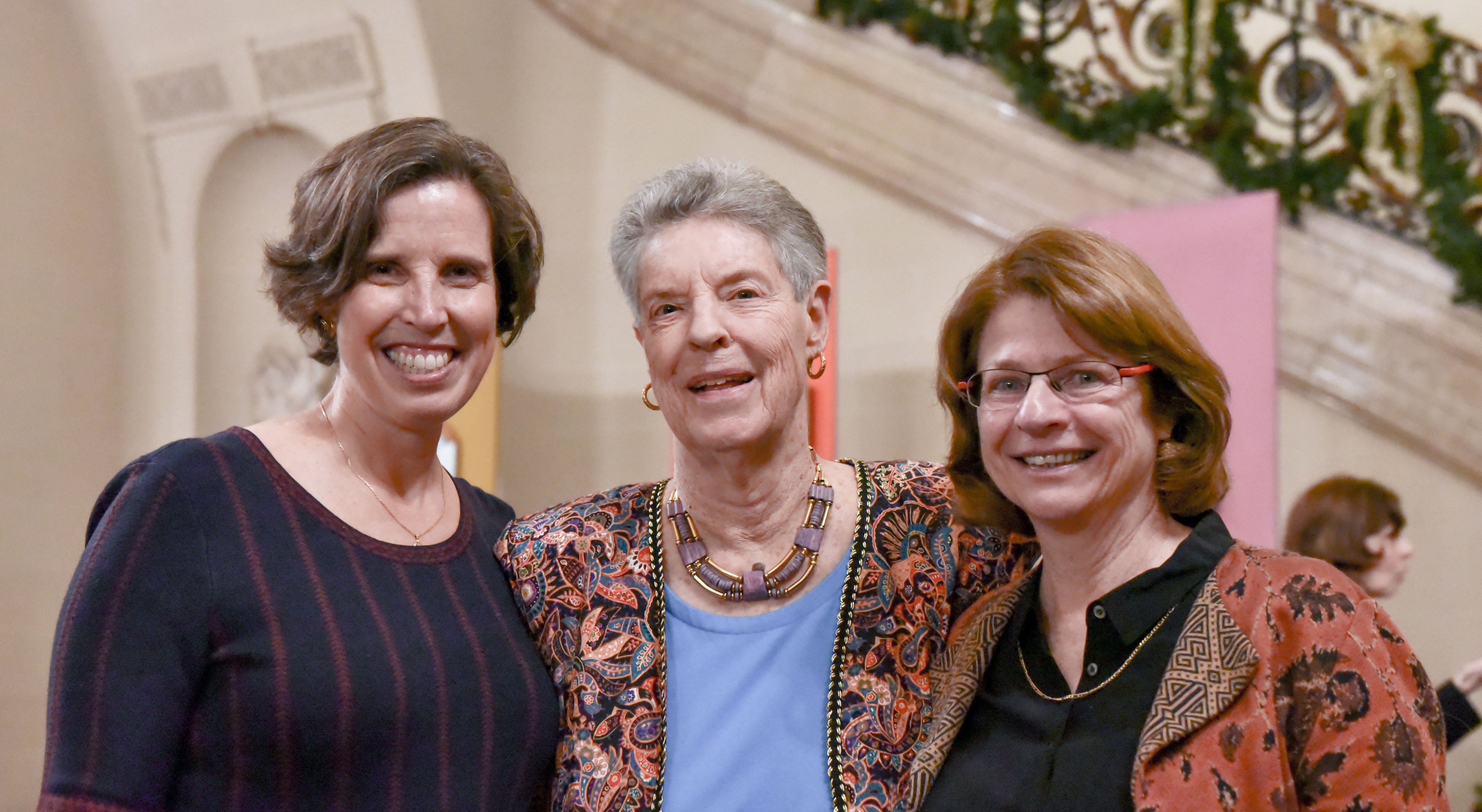 Three women smiling for the camera in the great hall.