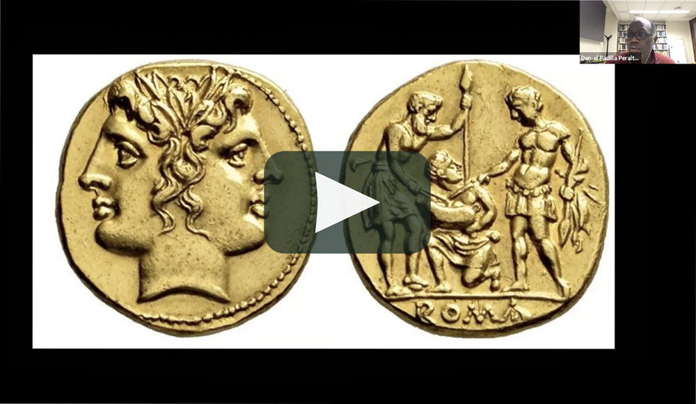 Video still from online lecture showing male speaker and a slide of two gold coins