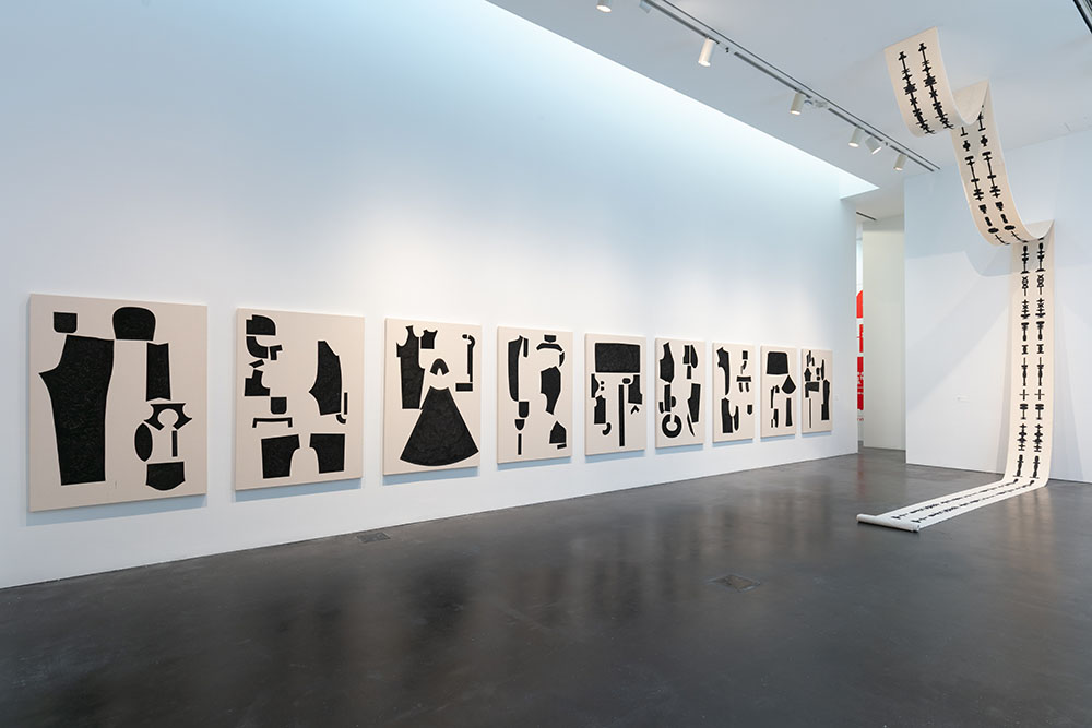Installation view of various artworks haning on walls and draped from the ceiling.