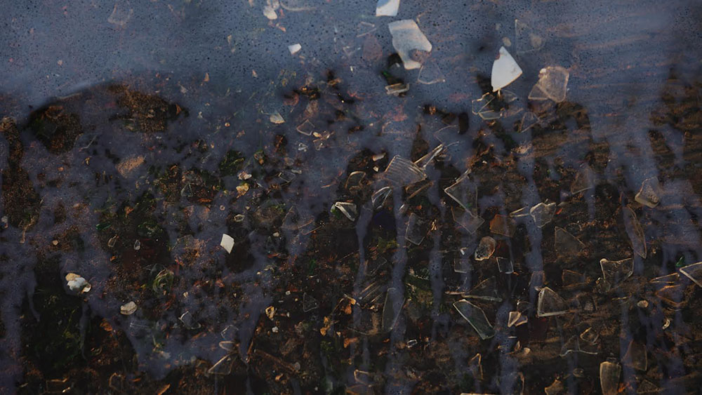 Pieces of broken glass underneath water.