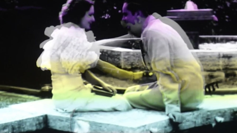Movie still of two seated figures talking.