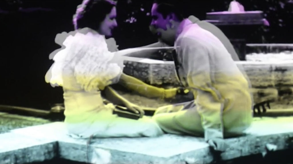 Movie still of two seated figures talking.